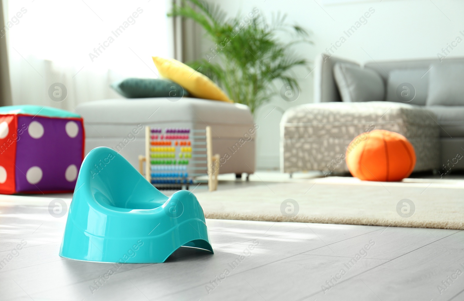 Photo of Modern blue potty on floor in nursery room. Toilet training