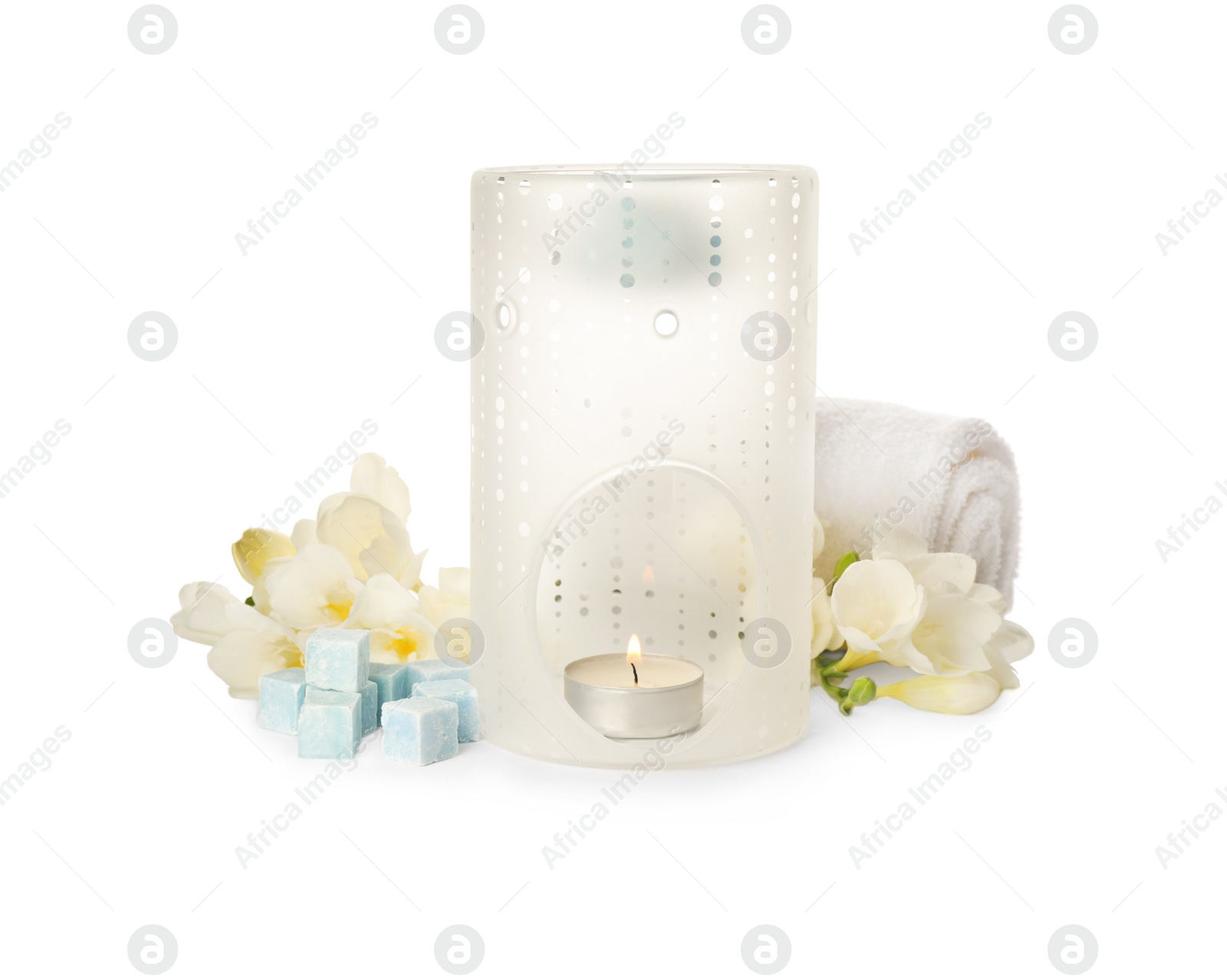 Photo of Stylish aroma lamp with essential wax cubes, flowers and towel on white background