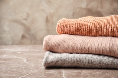 Photo of Stack of warm knitted clothes on table