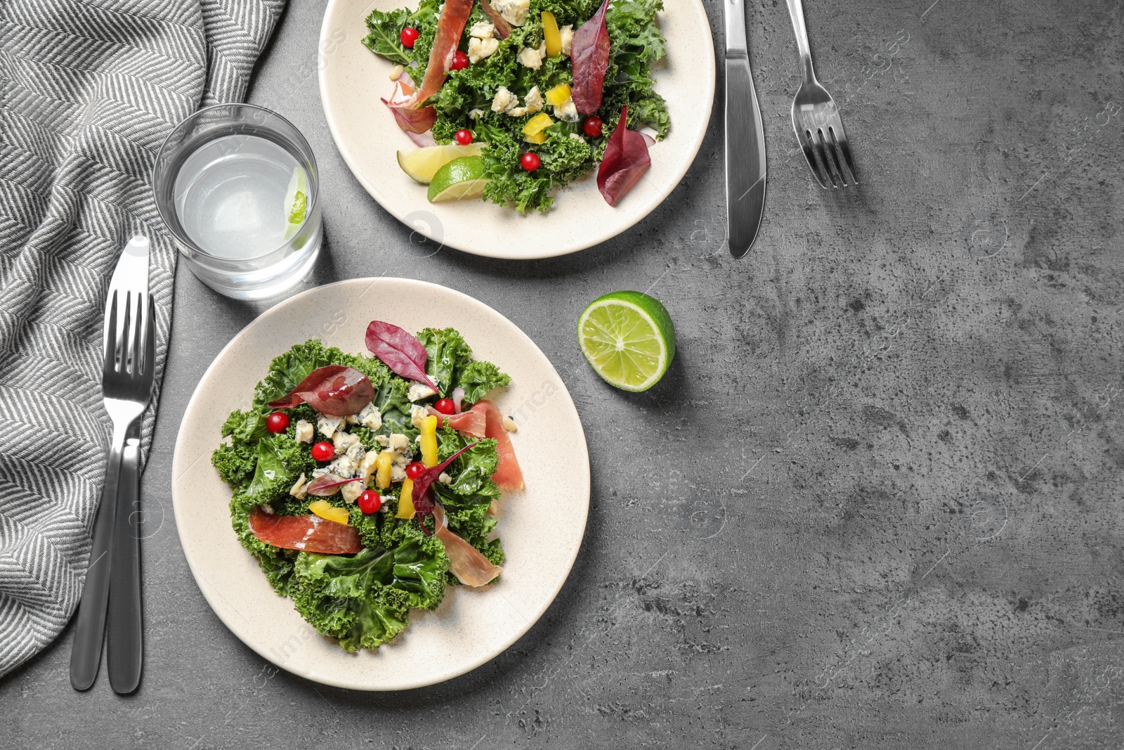 Photo of Tasty fresh kale salad on grey table, above view. Space for text