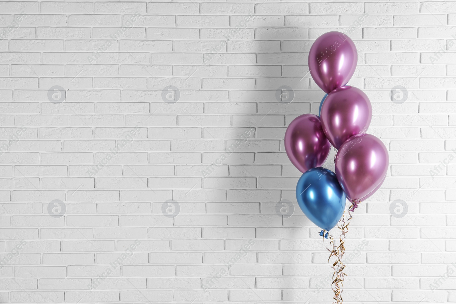 Photo of Bright colorful balloons near brick wall, space for text. Party time