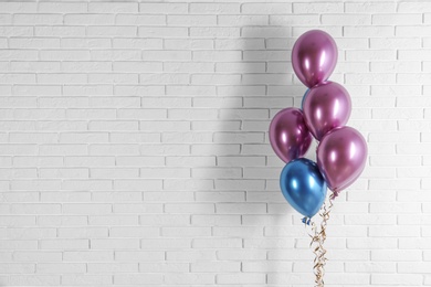 Bright colorful balloons near brick wall, space for text. Party time