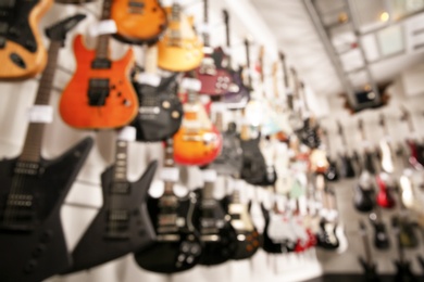 Photo of Rows of different guitars in music store, blurred view