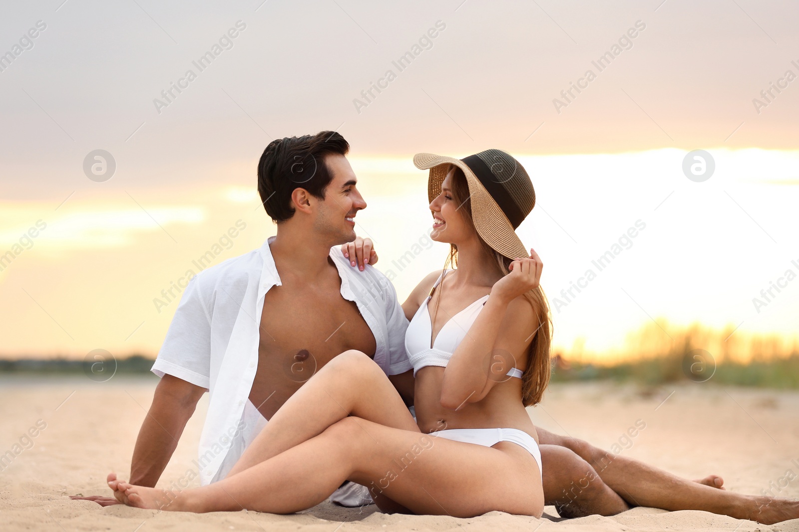 Photo of Happy young couple relaxing together on sea beach at sunset