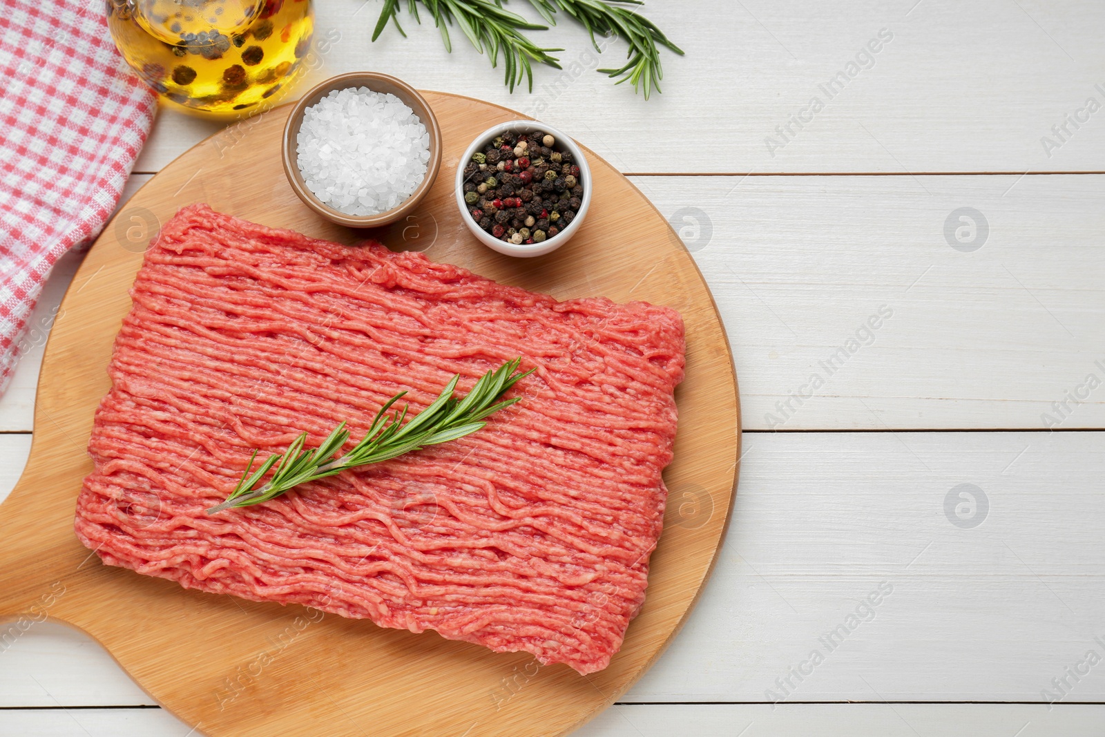 Photo of Raw fresh minced meat with rosemary and spices on white wooden table, flat lay. Space for text