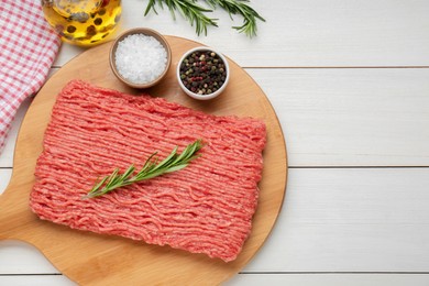 Raw fresh minced meat with rosemary and spices on white wooden table, flat lay. Space for text