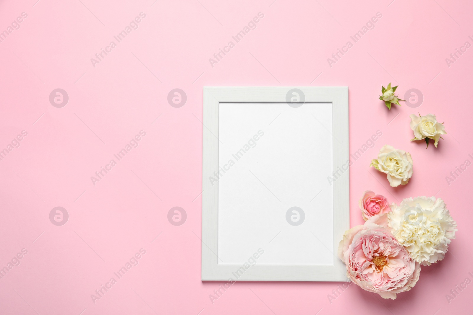 Photo of Empty photo frame and beautiful flowers on pink background, flat lay. Space for design