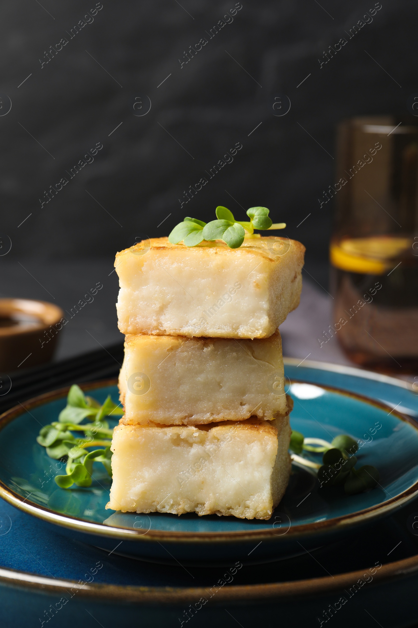 Photo of Delicious turnip cake with microgreens served on black table