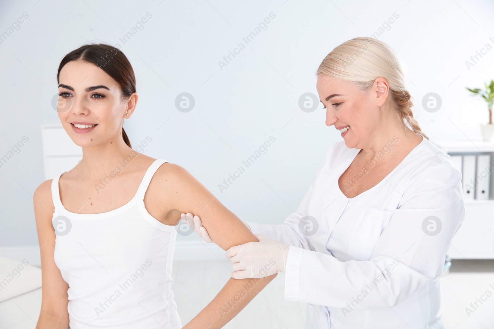 Photo of Dermatologist examining young patient's birthmark in clinic