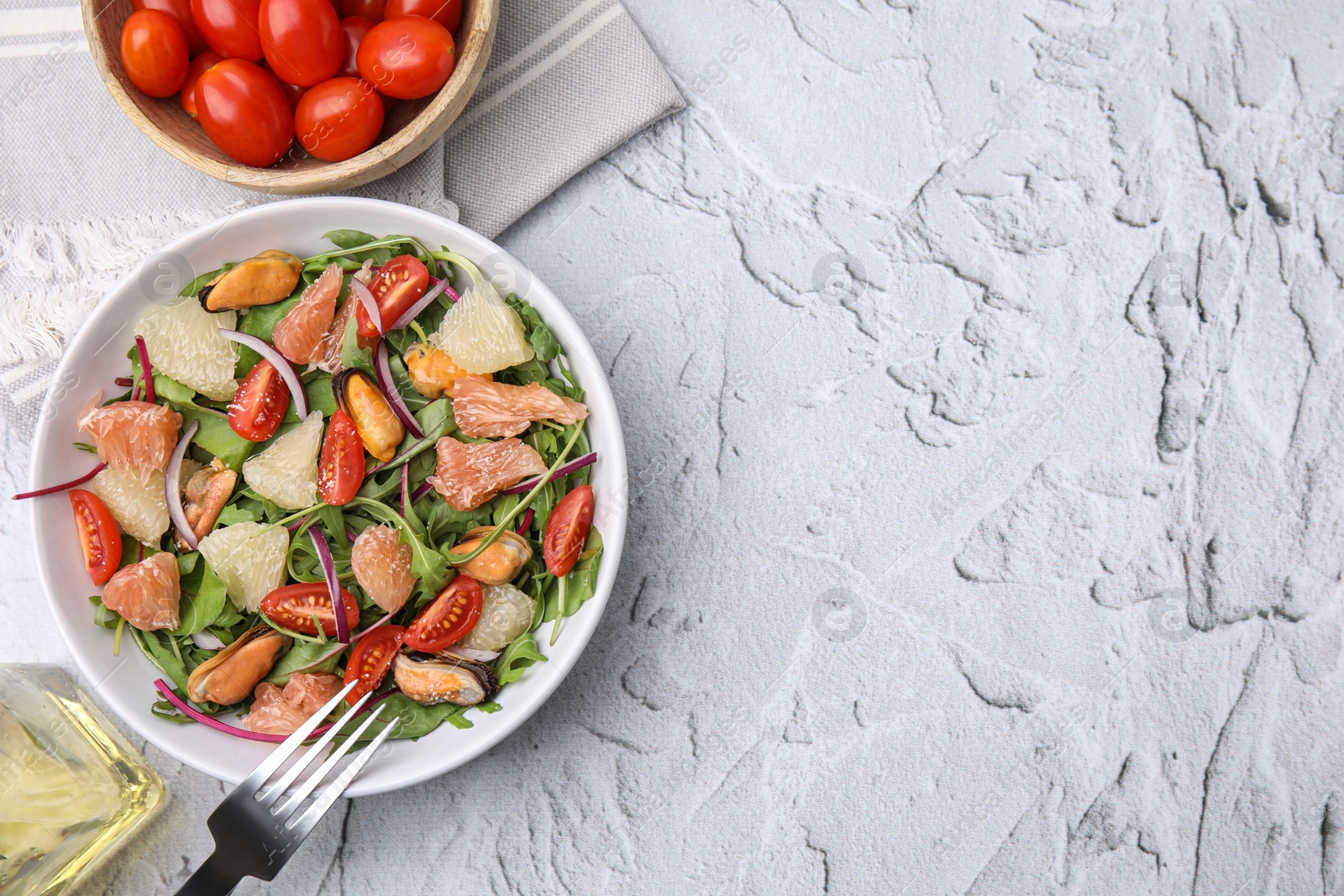 Photo of Delicious pomelo salad with tomatoes and mussels served on white textured table, flat lay. Space for text