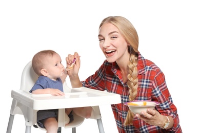 Photo of Woman feeding her child in highchair against white background. Healthy baby food