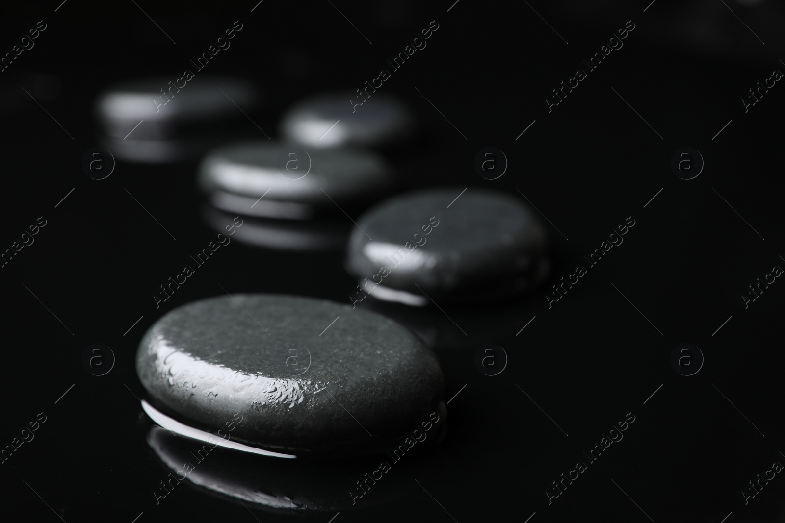 Photo of Wet spa stones on black background. Space for text