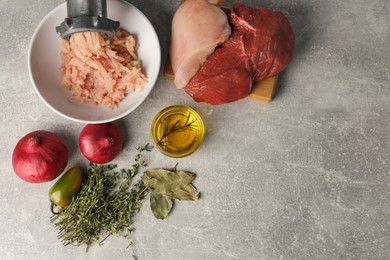 Metal meat grinder with chicken mince and products on light grey table, flat lay. Space for text