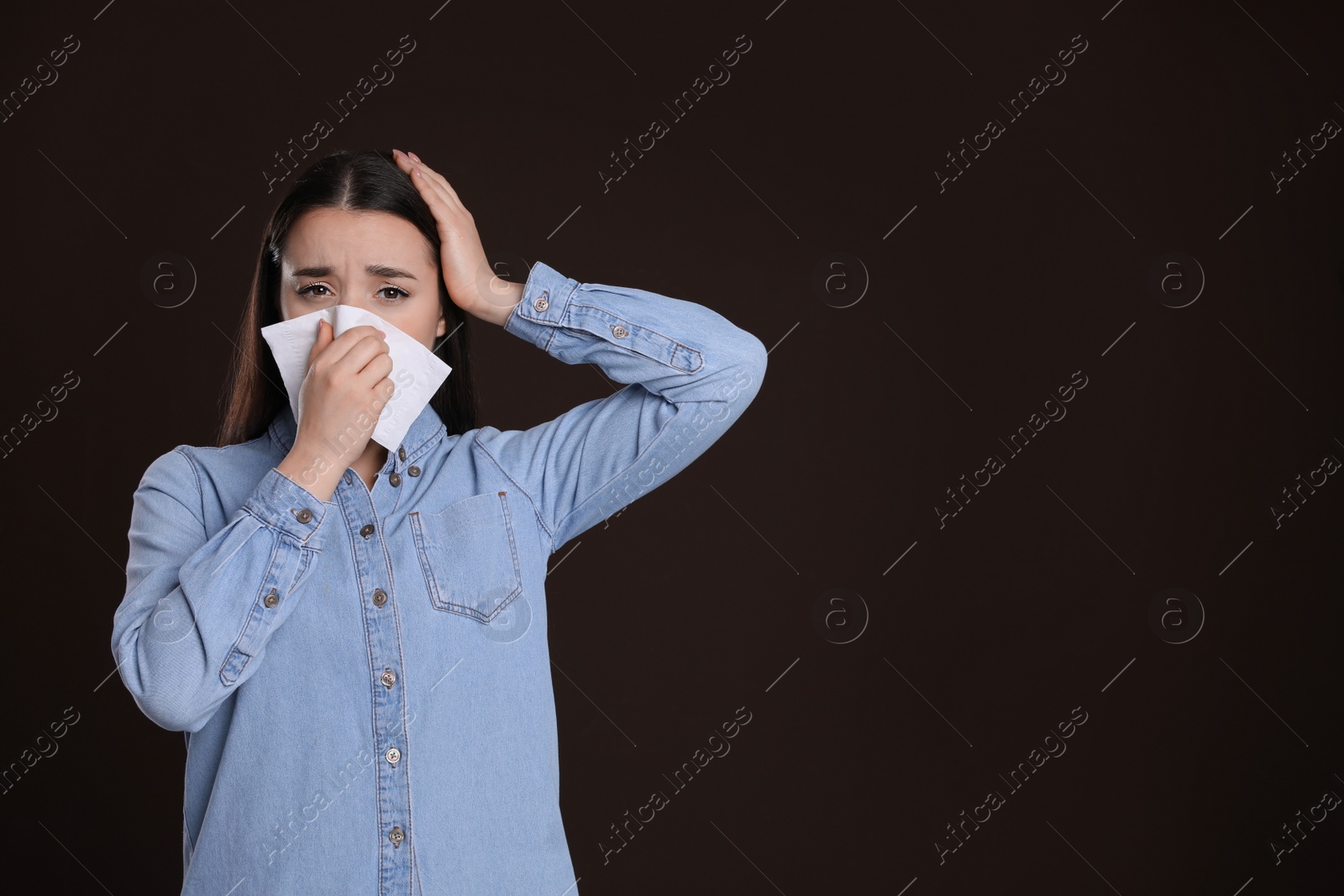 Photo of Young woman suffering from cold on dark background, space for text