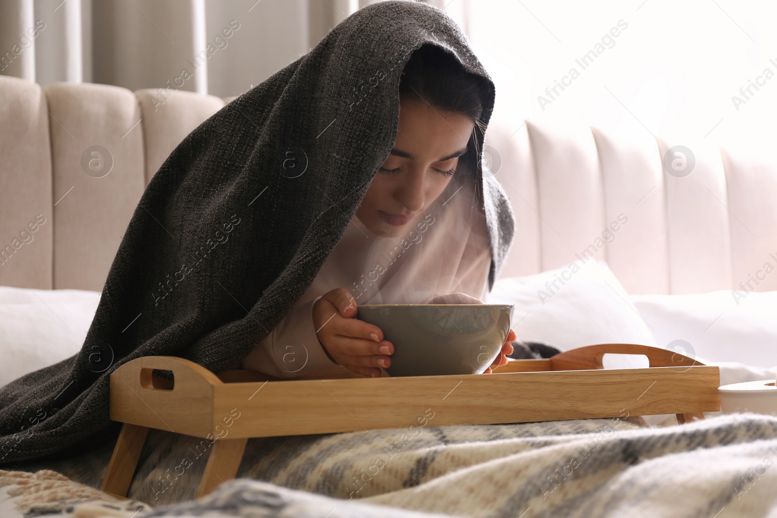 Photo of Woman with plaid doing inhalation above bowl on bed