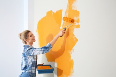 Photo of Happy woman painting wall indoors, space for text. Home repair
