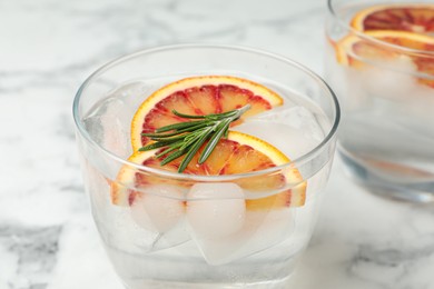 Photo of Delicious refreshing drink with sicilian orange and rosemary on white marble table, closeup