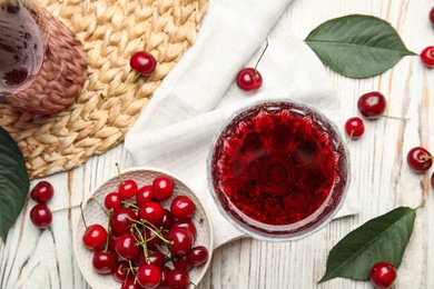 Delicious cherry wine with ripe juicy berries on white wooden table, flat lay