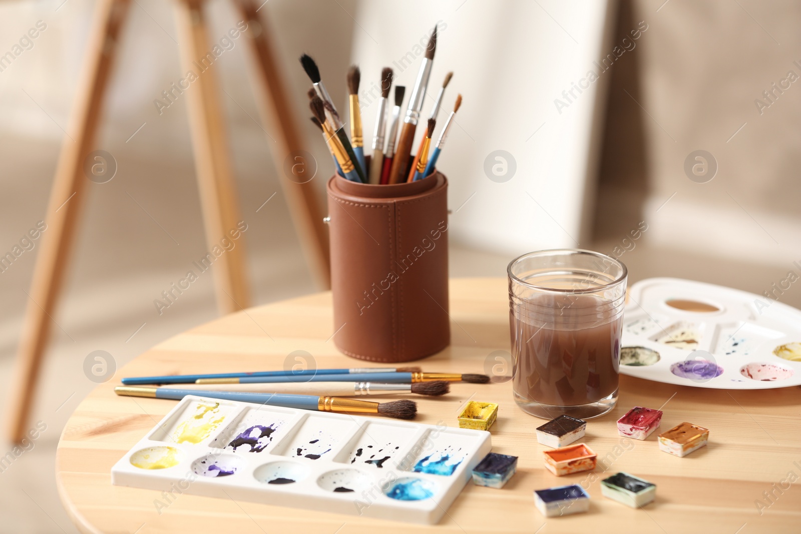 Photo of Composition with watercolor paints on wooden table in workshop