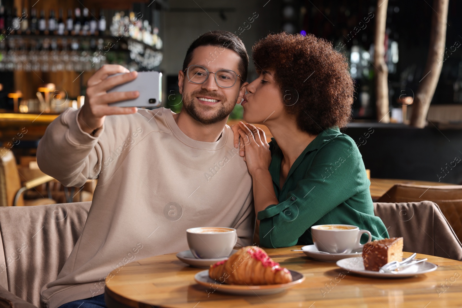 Photo of International dating. Happy couple taking selfie in cafe