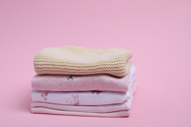 Photo of Stack of clean baby clothes on pink background. Space for text