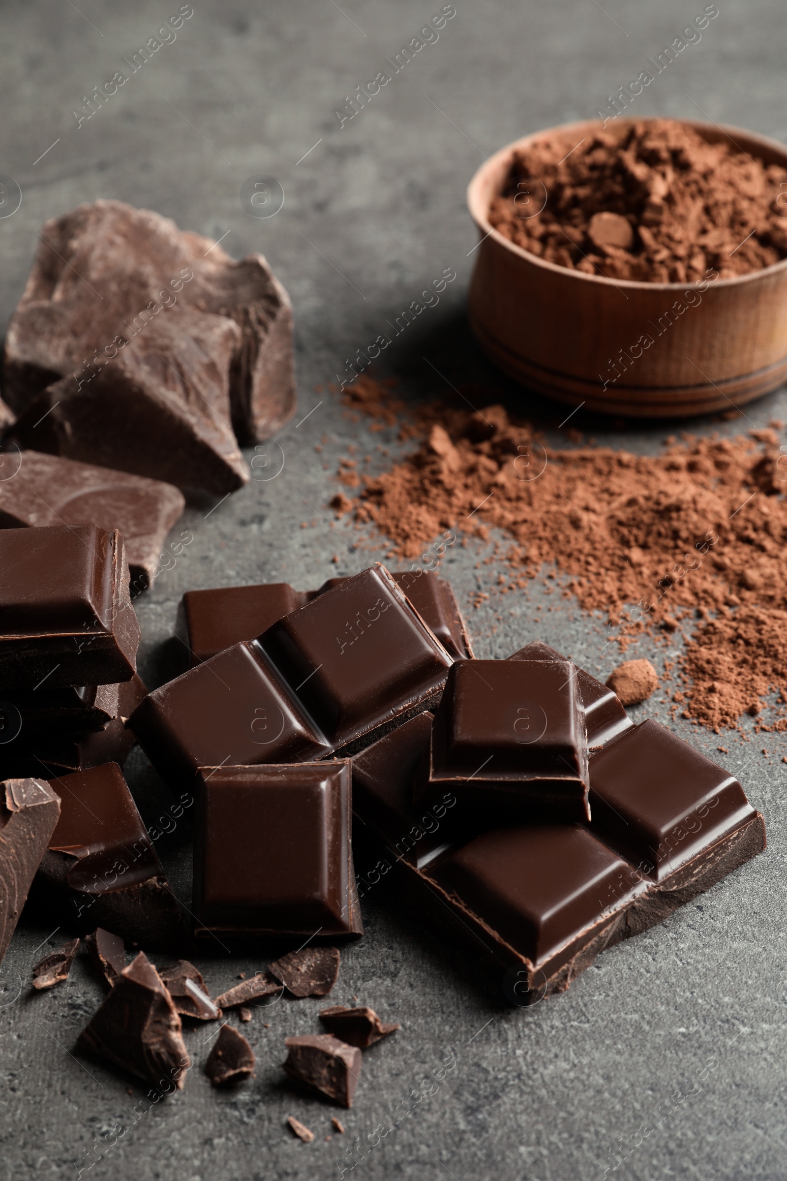 Photo of Pieces of chocolate and cocoa powder on grey background