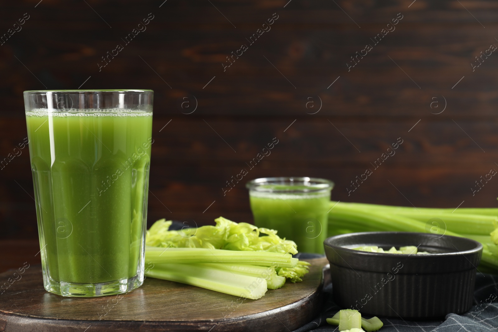 Photo of Glasses of delicious celery juice and vegetables on wooden board, closeup