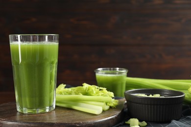 Glasses of delicious celery juice and vegetables on wooden board, closeup