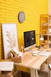 Photo of Stylish home office interior with comfortable workplace near yellow brick wall