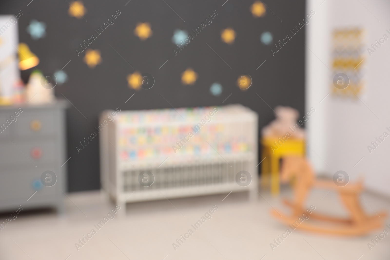 Photo of Blurred view of cute baby room interior with modern crib and rocking horse