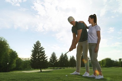 Happy couple playing golf on green course, space for text