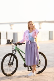 Photo of Young woman with bicycle in city on sunny day