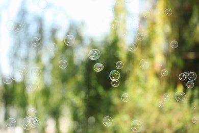 Photo of Beautiful translucent soap bubbles outdoors on sunny day