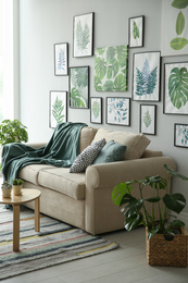 Photo of Beautiful artworks and comfortable couch in stylish room. Interior design