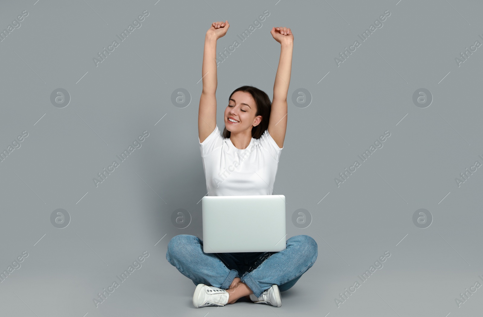 Photo of Young woman with modern laptop on grey background