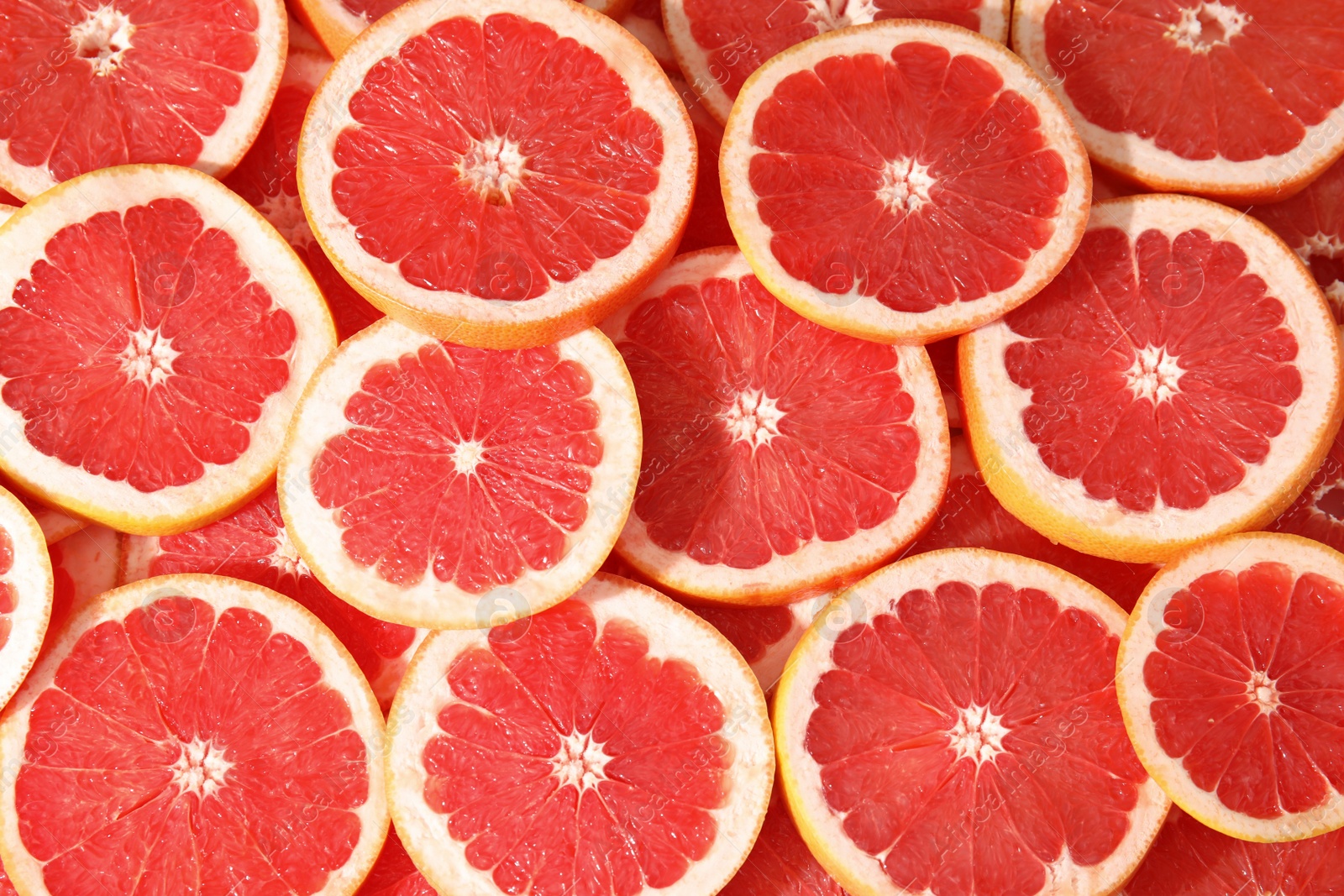 Photo of Many sliced fresh grapefruits as background, top view