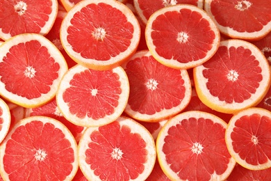 Many sliced fresh grapefruits as background, top view