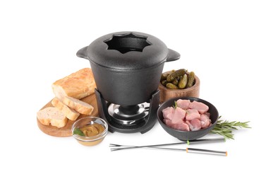 Photo of Fondue pot with oil, forks, raw meat pieces and other products isolated on white