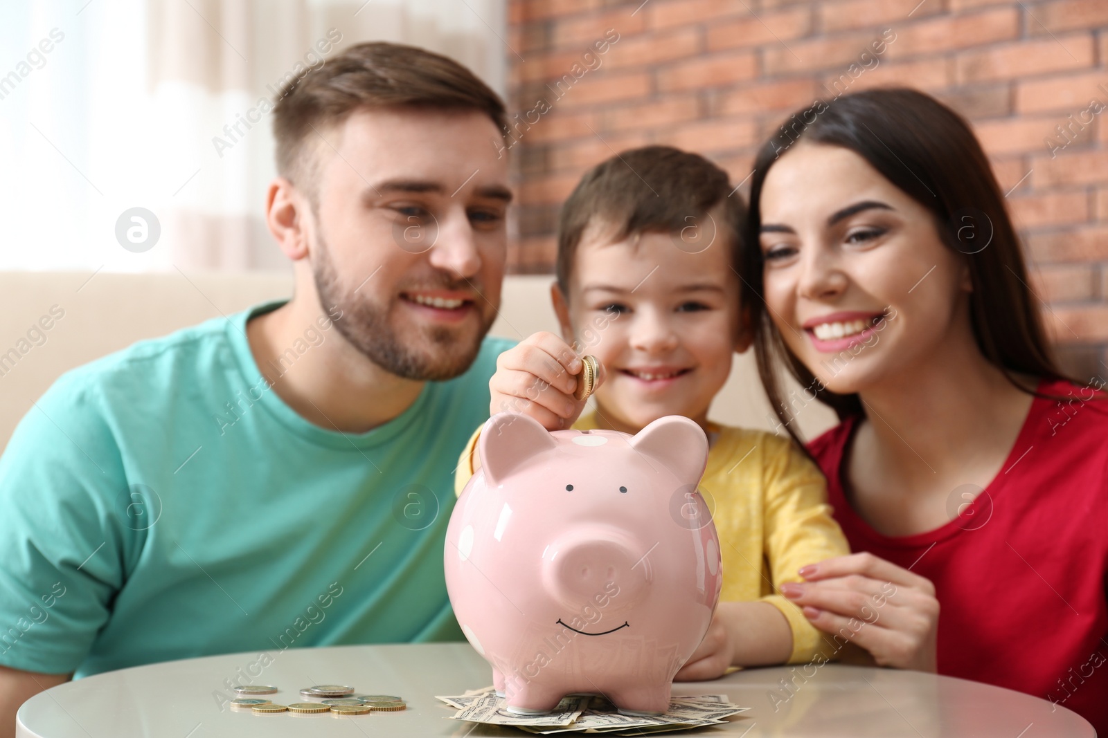 Photo of Happy family with piggy bank and money at home