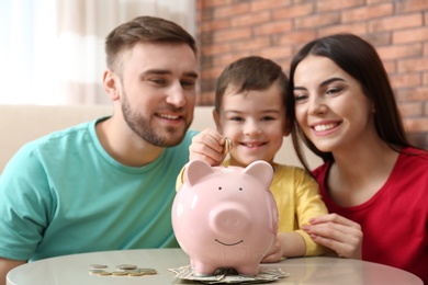 Photo of Happy family with piggy bank and money at home