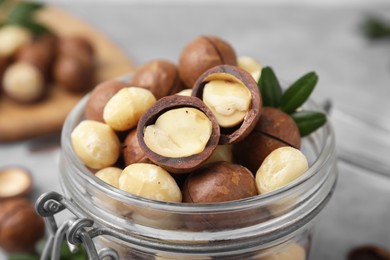 Photo of Tasty Macadamia nuts in jar on table, closeup view