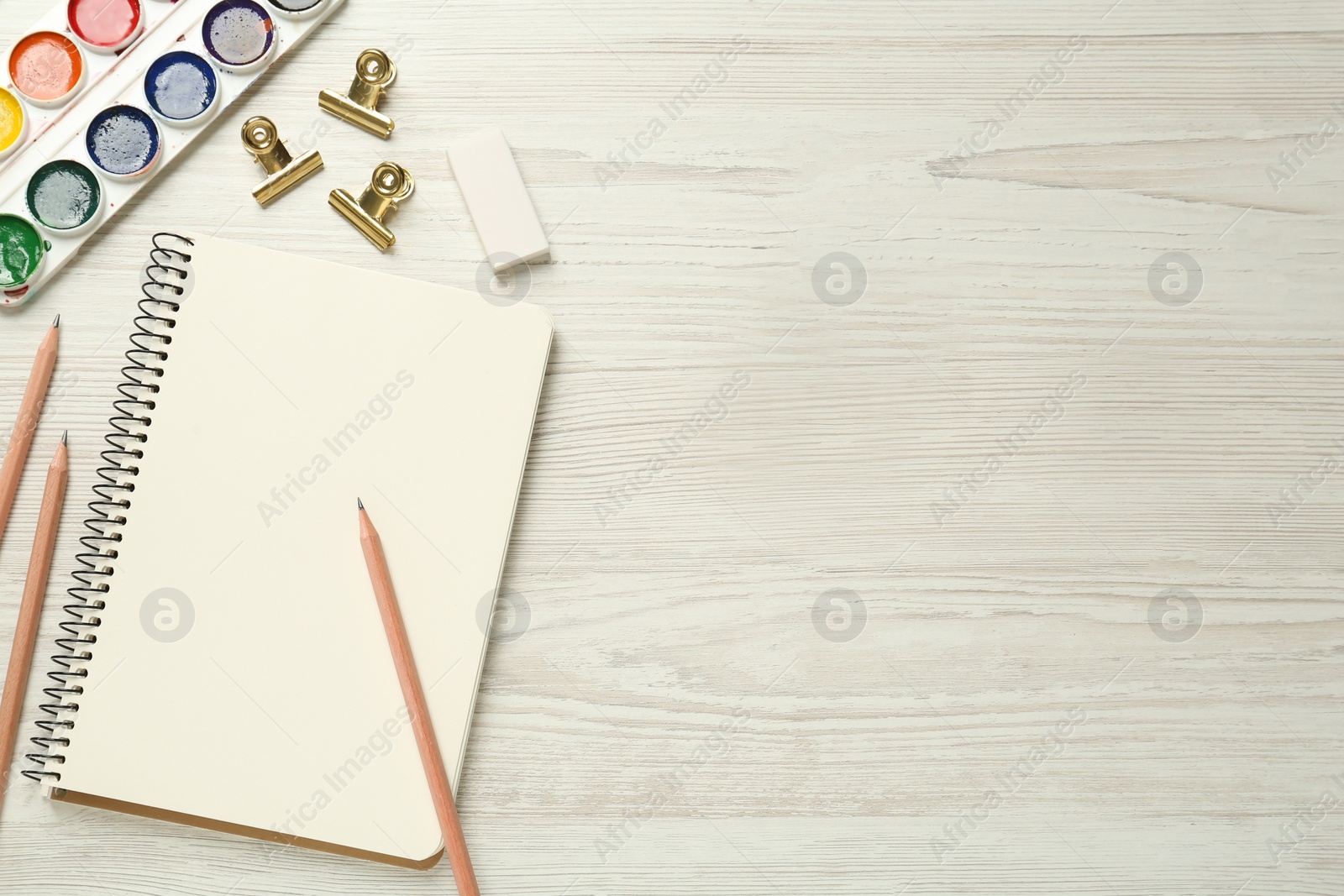 Photo of Flat lay composition with blank sketchbook on white wooden table. Space for text