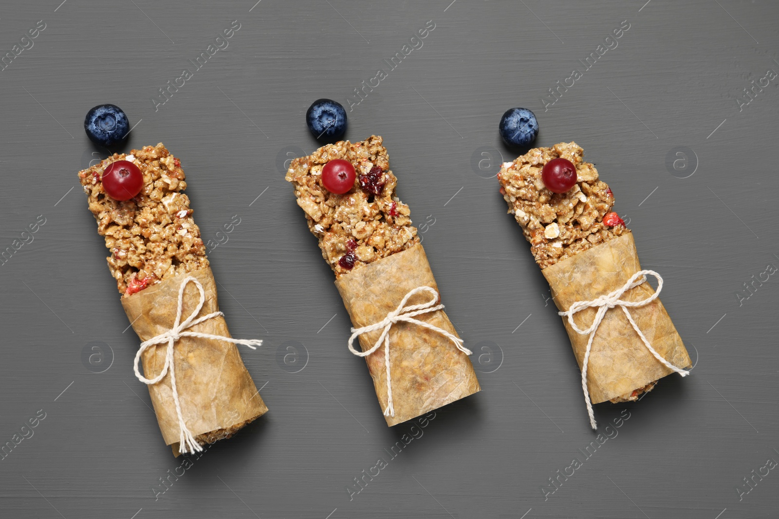 Photo of Tasty granola bars on grey wooden table, flat lay