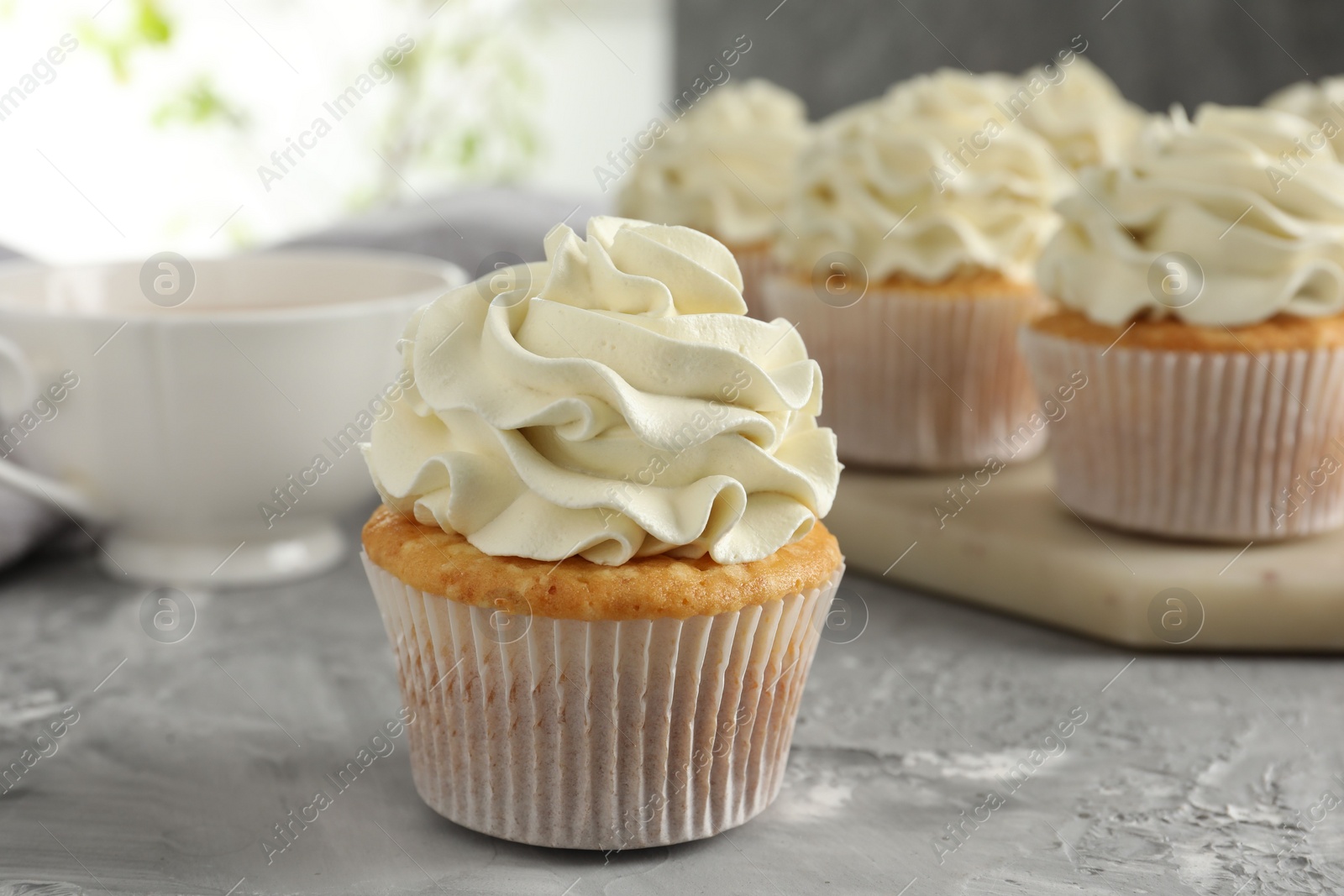 Photo of Tasty cupcakes with vanilla cream on grey table, closeup