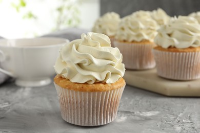 Tasty cupcakes with vanilla cream on grey table, closeup