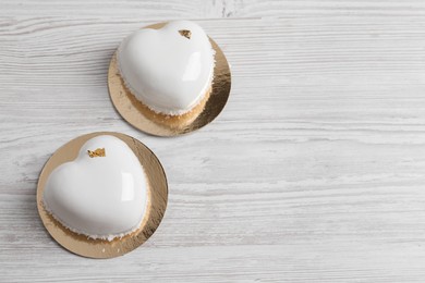 St. Valentine's Day. Delicious heart shaped cakes on white wooden table, flat lay. Space for text