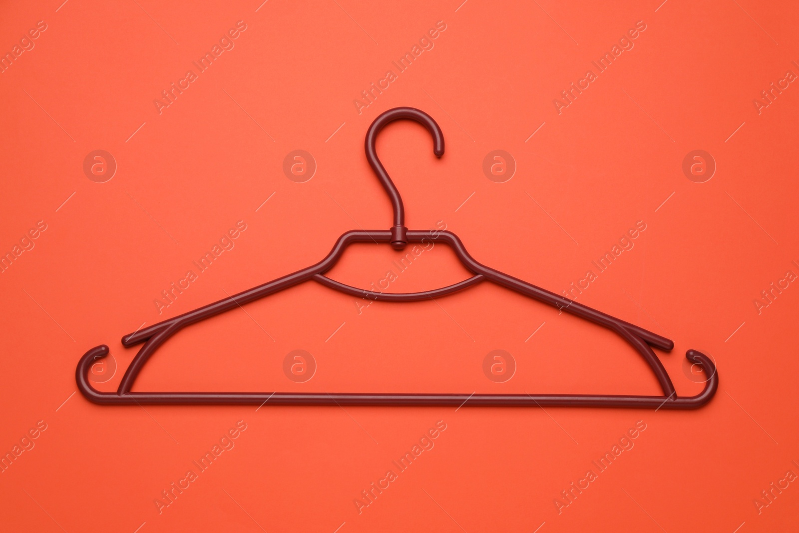 Photo of Empty clothes hanger on red background, top view