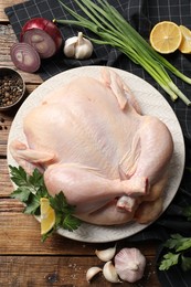 Photo of Fresh raw chicken with different products on wooden table, flat lay