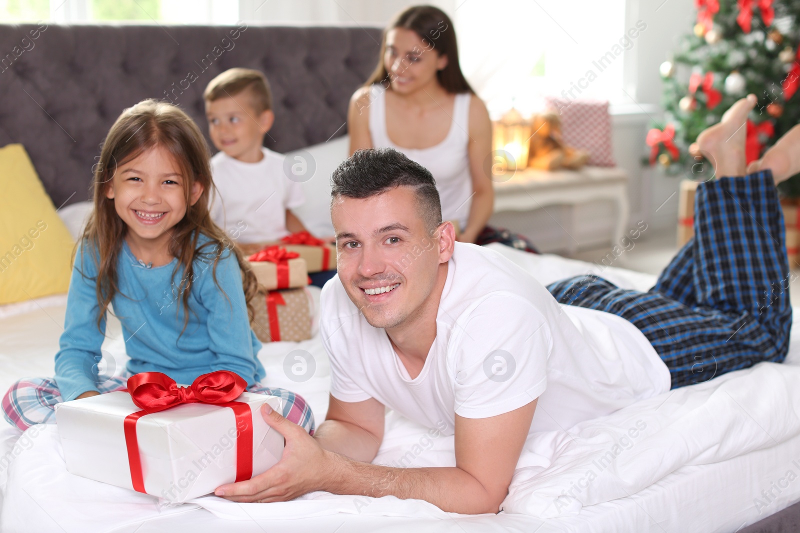 Photo of Happy parents and children exchanging gifts on Christmas morning at home