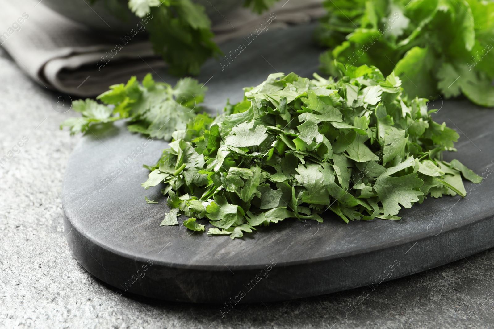 Photo of Cut fresh green cilantro on grey table, closeup